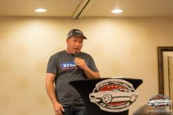 Brian, at the podium with microphone, at the SEMA Pro-Touring Dinner chatting with the drivers