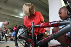 Mary featured with a middle schooler handling a bike repair.